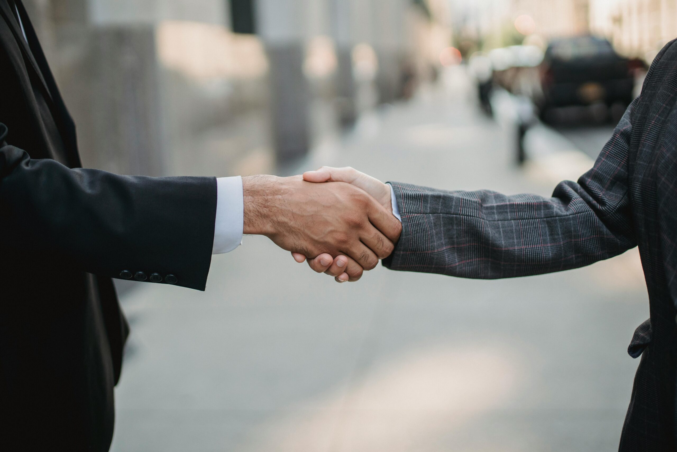 Close-up of a business handshake between professionals outdoors.